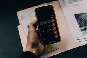holding iphone calculator over documents